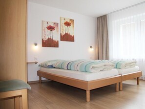 A modern bedroom with a wooden bed, two wall-mounted light fixtures, and two paintings. - Adonis Appartement/Fewo, Dusche oder Bad, WC 4-Bettwohnung by Interhome (Saas-Fee)