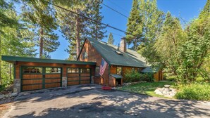 A wooden cabin with a garage, surrounded by trees and a stone pathway. - Tahoe Vista Getaway: Lake View & Hot Tub & Deck (Tahoe Vista)