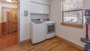A laundry room with a washer and dryer, a window with blinds, and a door leading to another room. - Tahoe Vista Getaway: Lake View & Hot Tub & Deck (Tahoe Vista)