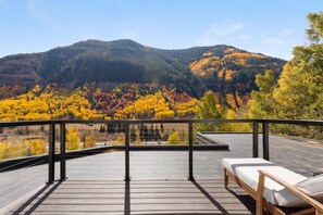 A deck with a view of a forested mountain range. - East Vail Retreat | Hot Tub, Fire Pit & Views (Vail)