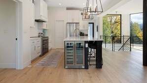Una cocina moderna con una isla central, electrodomésticos de acero inoxidable y vistas al exterior.