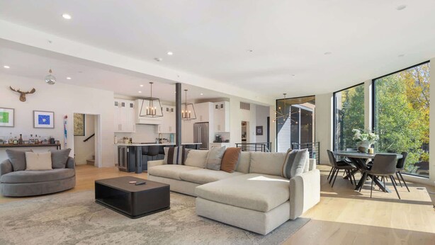 Una sala moderna con un sofá modular, una mesa de centro y un comedor con mesa y sillas.