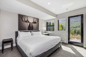 Una camera da letto moderna con un letto grande, un comodino, una lampada e un quadro con le corna di un alce.