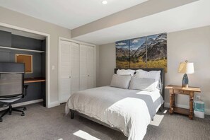 Ein Schlafzimmer mit einem Bett, einem Schreibtisch, einem Stuhl, einem Kleiderschrank und einem Bild an der Wand.
