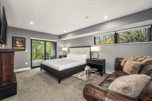 Une chambre à coucher moderne avec un grand lit, un canapé en cuir, une table basse et un téléviseur fixé au mur.