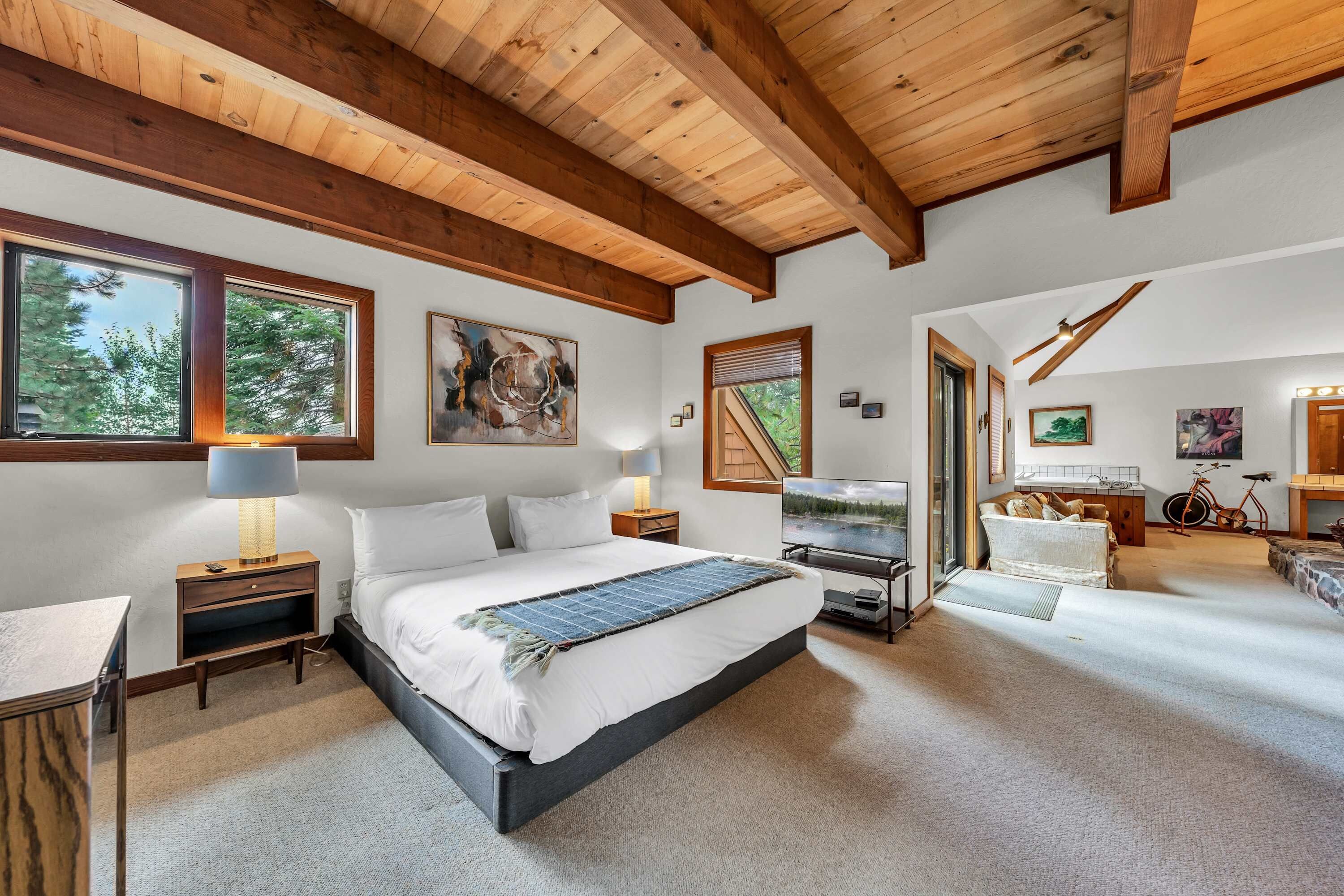 A spacious bedroom with a large bed, a television, and a bicycle in the corner.