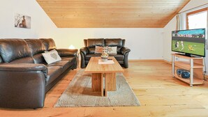 A loft-style living room with a wooden ceiling, two leather sofas, a coffee table, and a television on a wooden stand. - Weissmies Appartement/Fewo 5-Bettwohnung by Interhome (Saas-Grund)