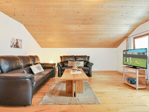 A loft-style living room with a wooden ceiling, two leather sofas, a coffee table, and a television on a wooden stand. - Weissmies Appartement/Fewo 5-Bettwohnung by Interhome (Saas-Grund)