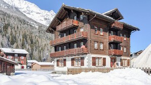 A multi-story wooden building with balconies, surrounded by snow and mountains. - Weissmies Appartement/Fewo 5-Bettwohnung by Interhome (Saas-Grund)