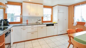 Una cucina con mobili bianchi, un piano di lavoro, un lavello e una zona pranzo con tavolo e sedie.