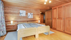 Camera da letto con rivestimento in legno, un letto matrimoniale, lampade ai comodini e un ampio armadio.