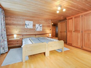 A wooden-paneled bedroom with a double bed, bedside lamps, and a large wardrobe. - Weissmies Appartement/Fewo 6-Bettwohnung by Interhome (Saas-Grund)