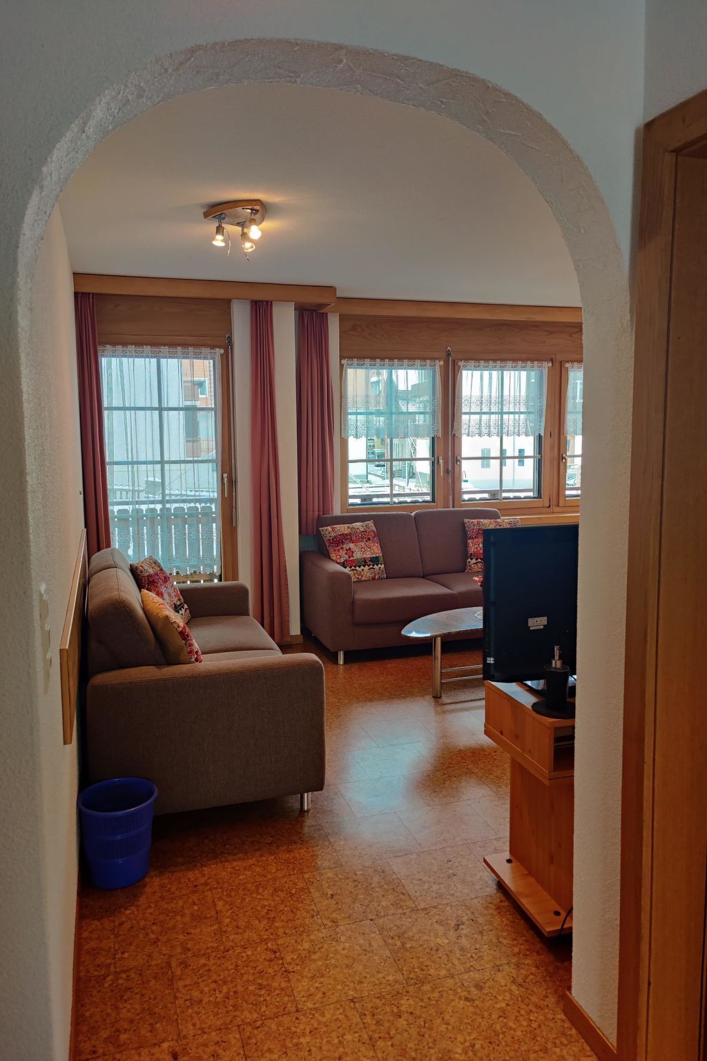 Una sala de estar con sofá, televisor y ventana con cortinas.