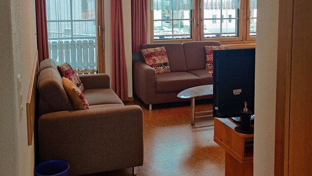 Un soggiorno con divano, televisore e finestra con tende.