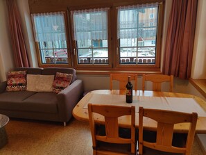 Ein gemütliches Wohnzimmer mit einer Couch, einem Holztisch und zwei Stühlen.