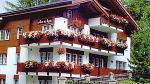 Un edificio a più piani con balconi decorati da fiori, un cartello con scritto 'Amethyst' e un muro di pietra di fronte.