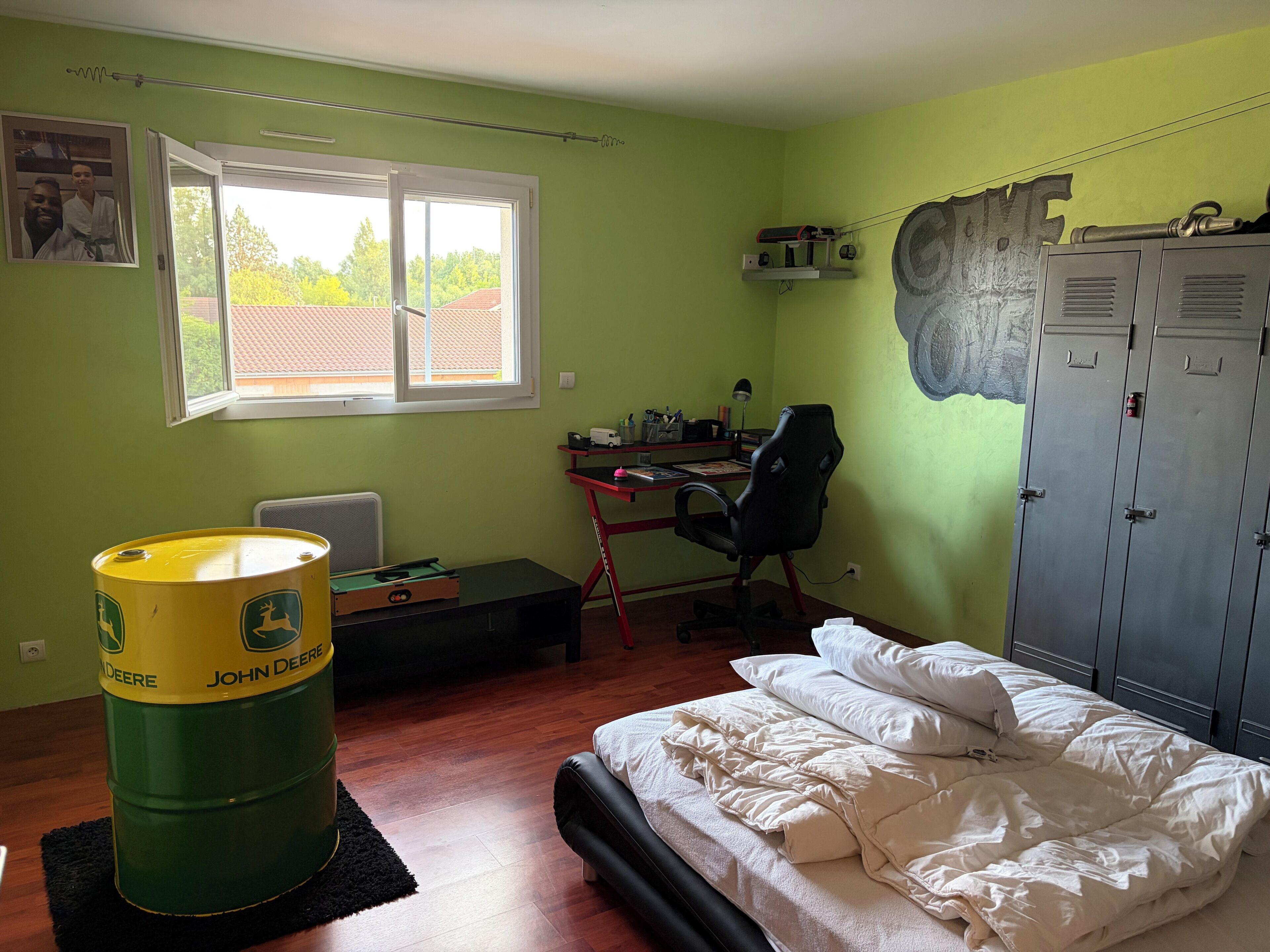 A room with a bed, a desk with a chair, a radiator, a window, and a wardrobe.