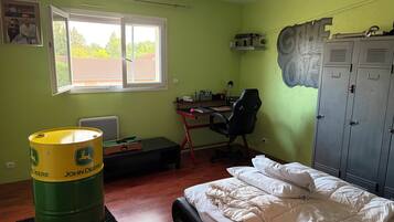 A room with a bed, a desk with a chair, a radiator, a window, and a wardrobe.