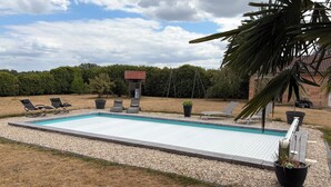 Ein rechteckiger Pool mit einer gefliesten Terrasse, umgeben von einem Kiesstreifen.
