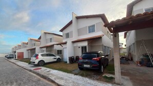 A residential area with modern houses, a paved road, and parked cars.