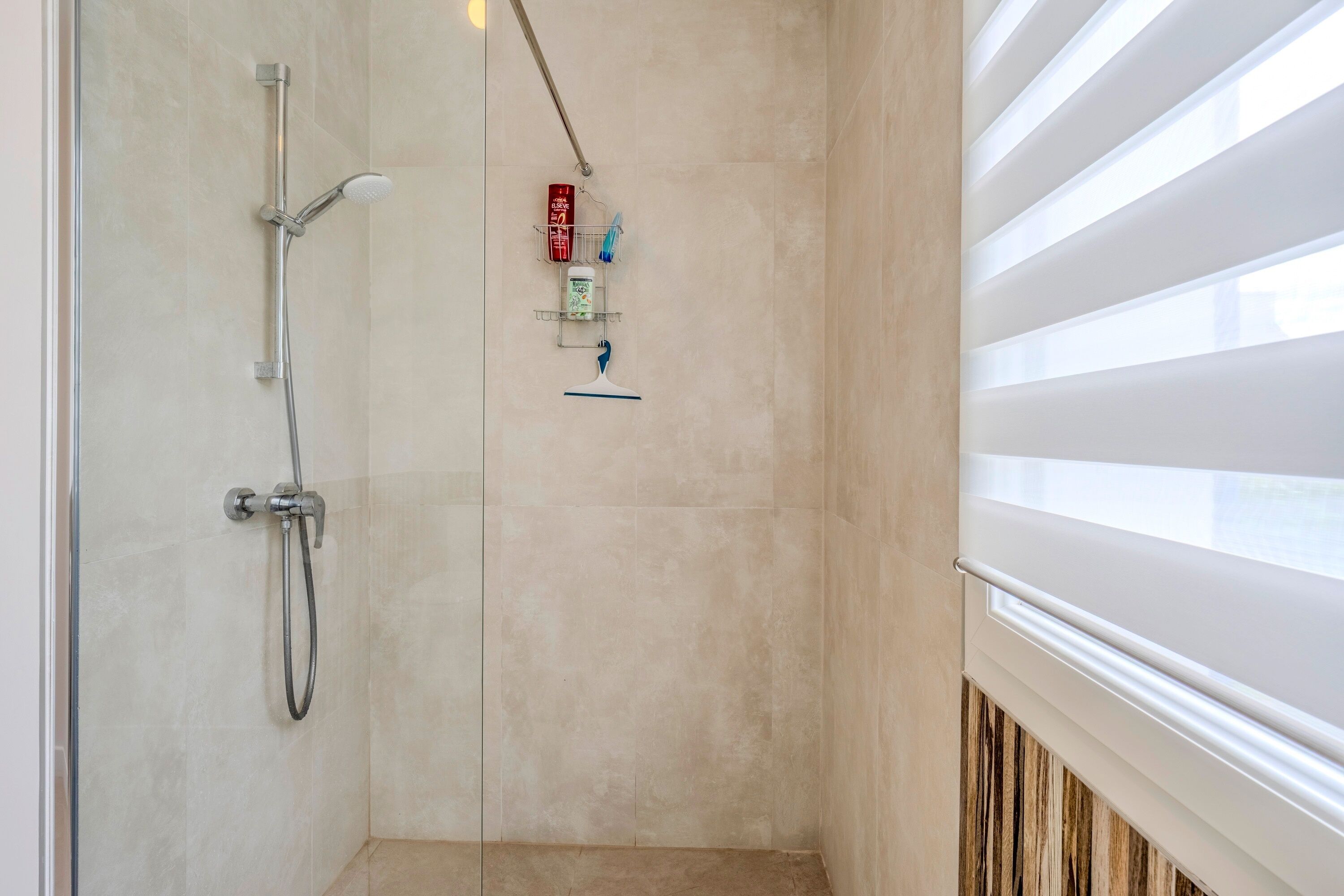 A shower area with a handheld showerhead, a wall-mounted faucet, and a towel rack with toiletries.
