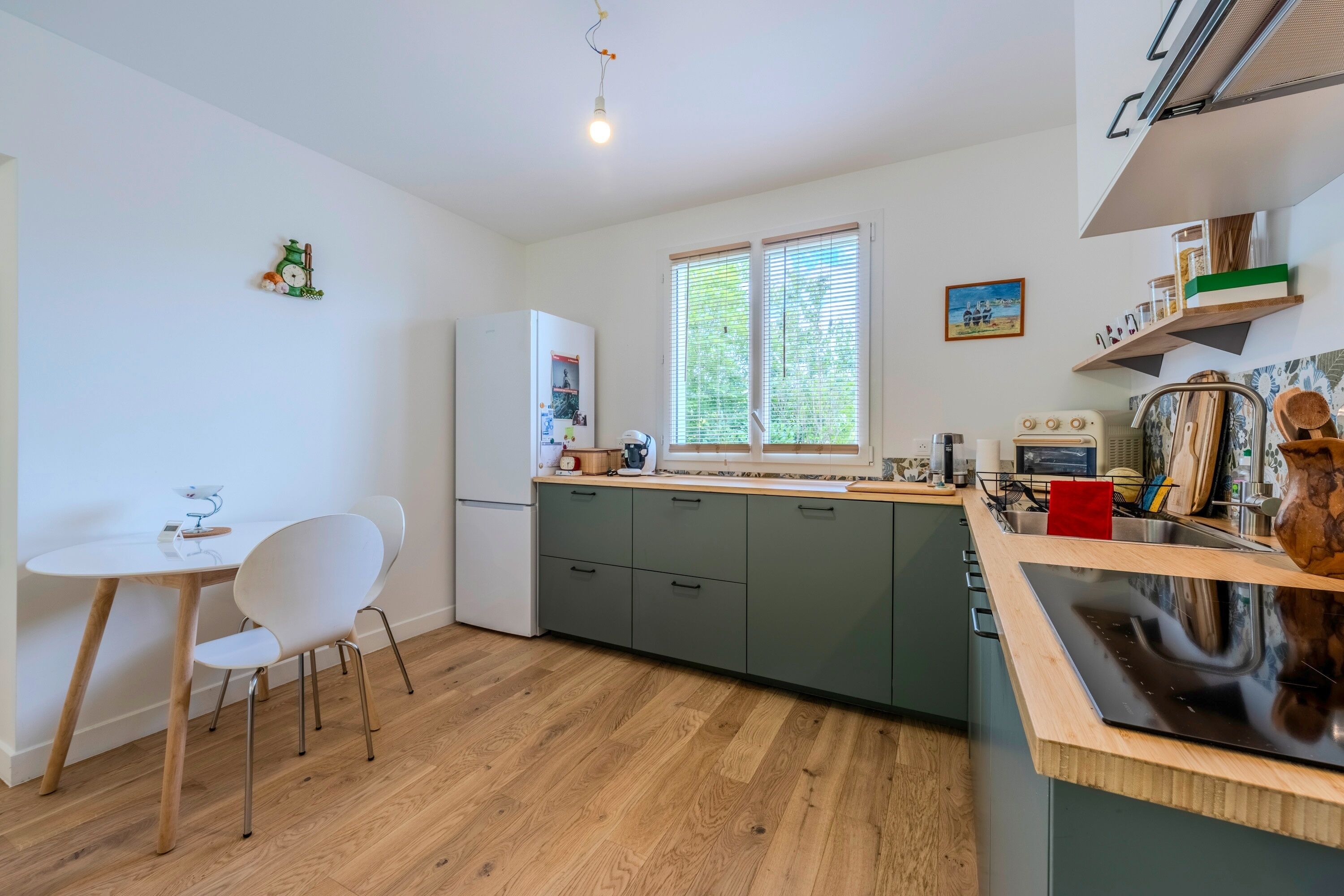 A modern kitchen with a wooden countertop, a built-in oven, and a window with blinds.