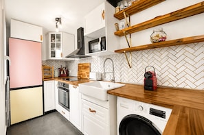 Eine kleine Küche mit Kühlschrank, Backofen, Mikrowelle, Spüle und Waschmaschine.