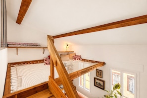 Ein Schlafzimmer im Loft-Stil mit einer Holztreppe, einem Etagenbett und einem kleinen Schreibtisch mit Lampe.
