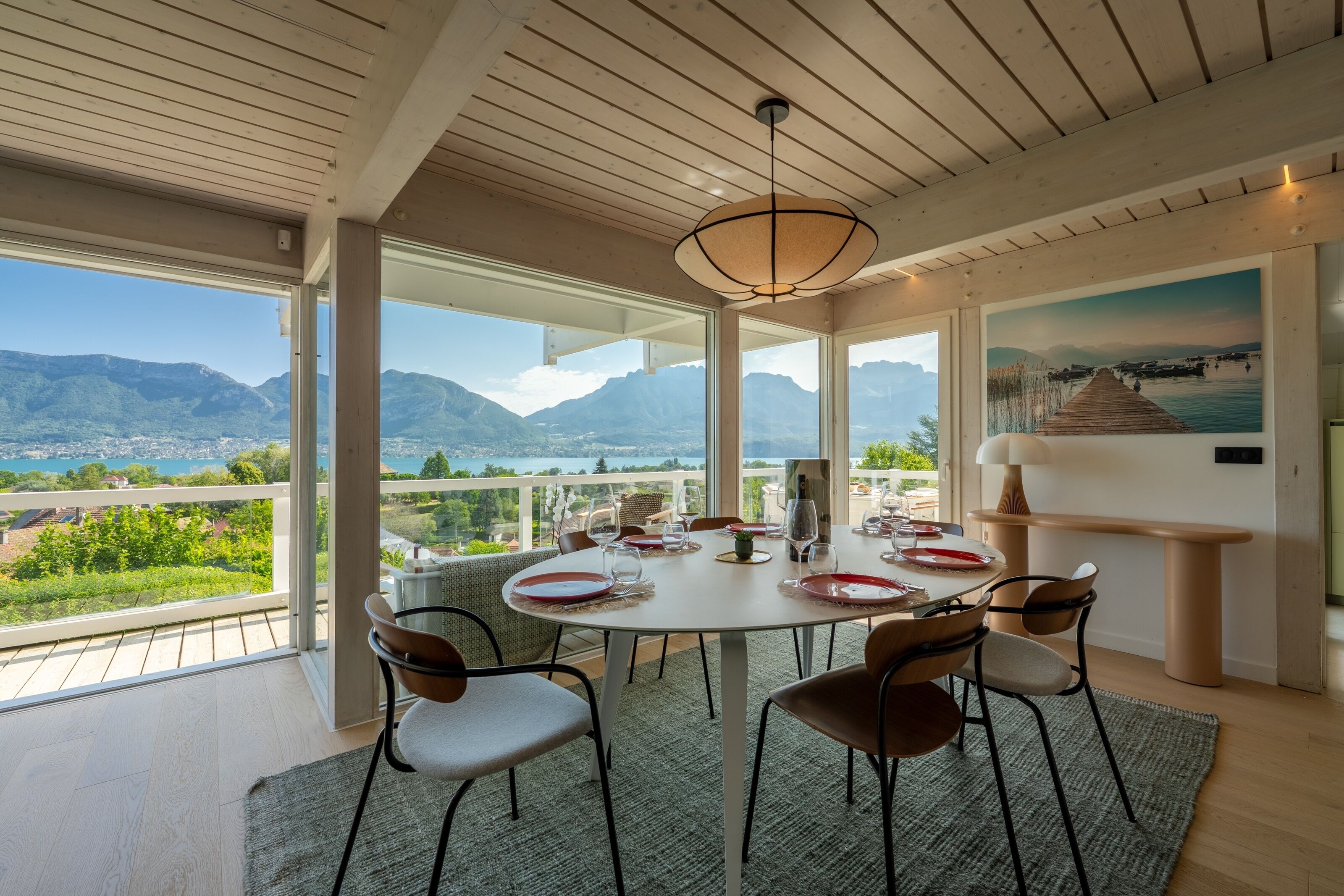 A dining area with a table set for six, overlooking a mountainous landscape.