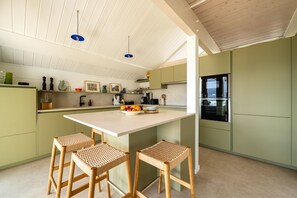 A modern kitchen with a central island, bar stools, and a built-in oven. - Villa Alba - Vue panoramique sur lac et montagnes (Sévrier)