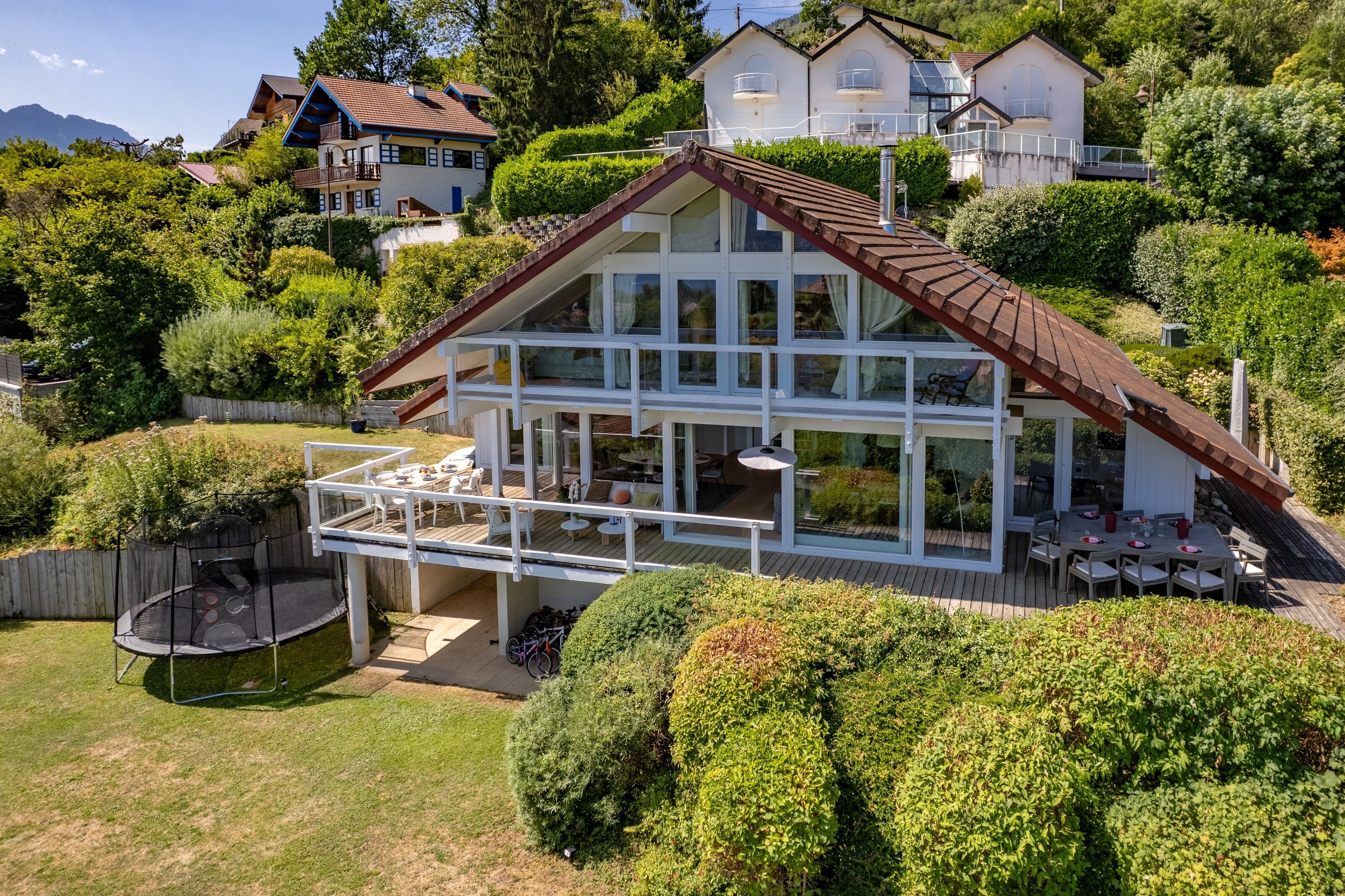 Una casa a due piani con un balcone, un cortile recintato e un trampolino.