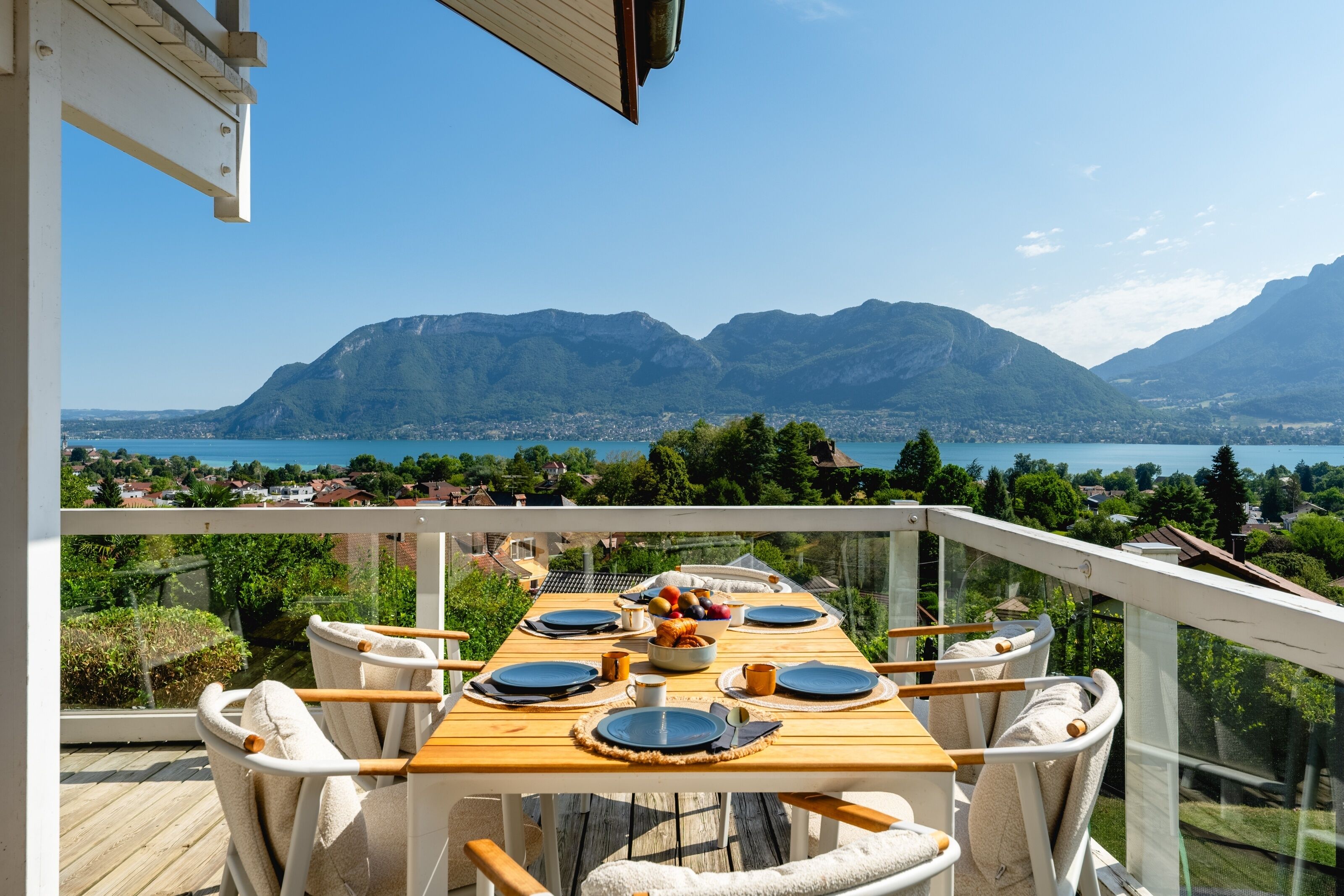 Ein Esstisch auf einem Balkon mit Blick auf Berge und einen See.