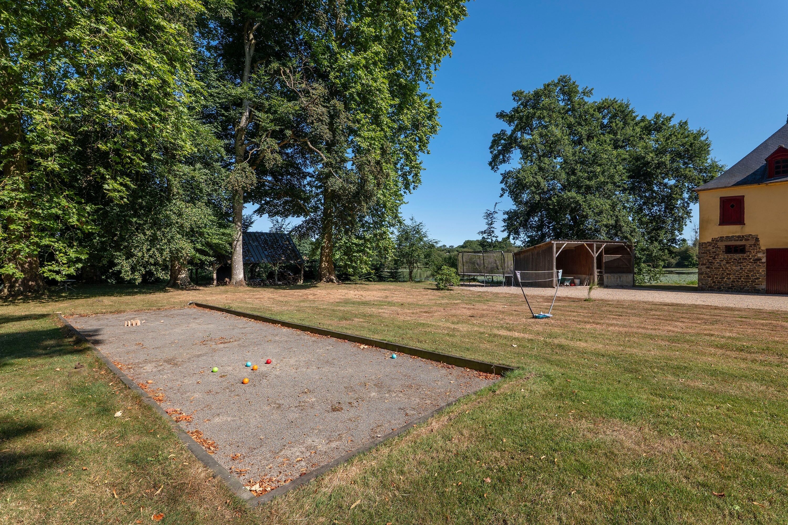 A courtyard with a croquet field, a covered seating area, and a building with a stone foundation.