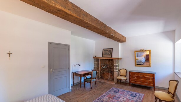Une pièce comprenant un lit, un bureau, une commode, une chaise, un tapis et une cheminée.
