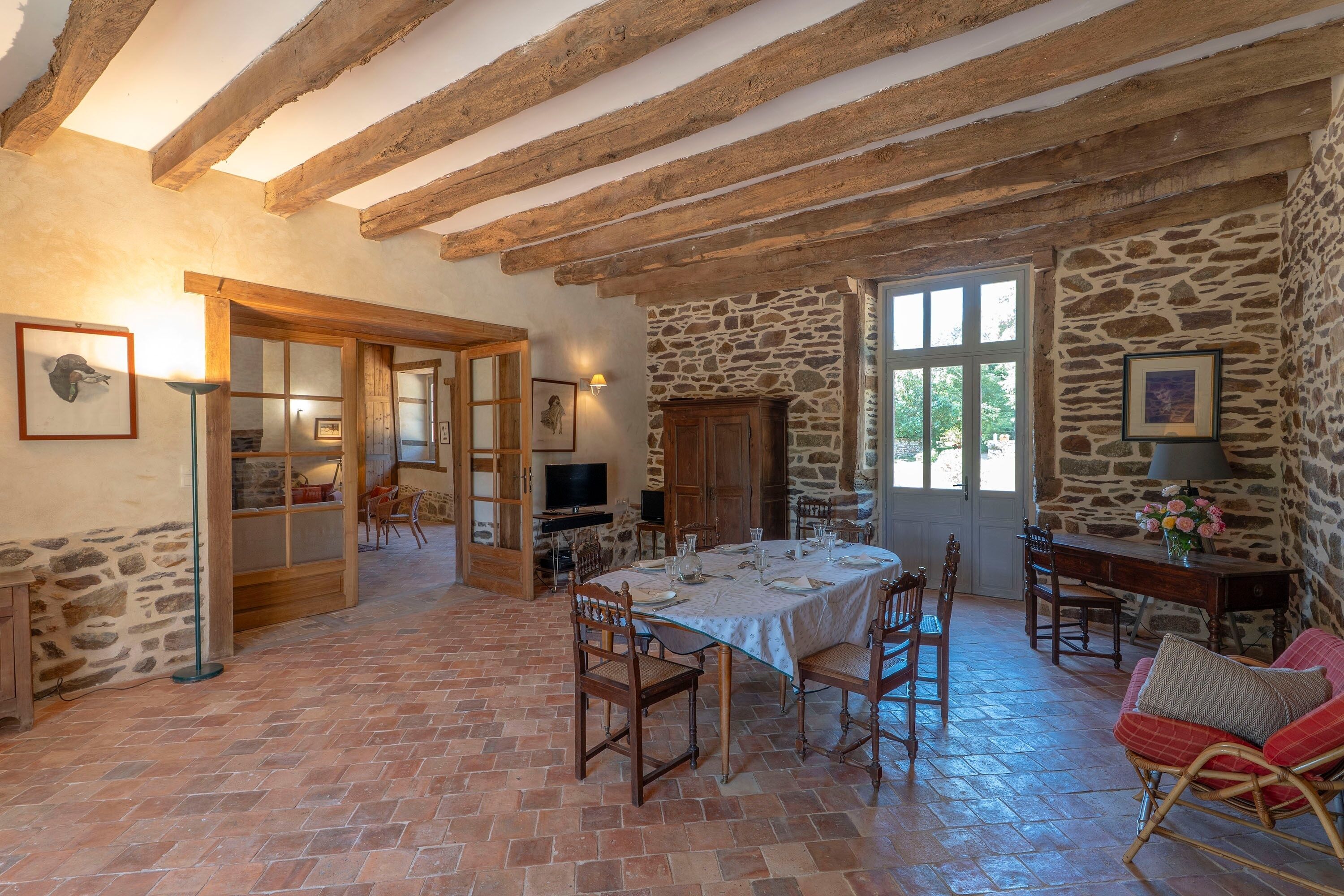 Un comedor rústico con vigas de madera a la vista, paredes de piedra y suelo de ladrillo.