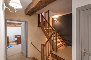 Een houten trap met een leuning, een lamp erboven en een vloerbedekt plateau.