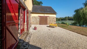 Un bâtiment à la façade en pierre, avec une porte rouge et une allée gravillonnée.