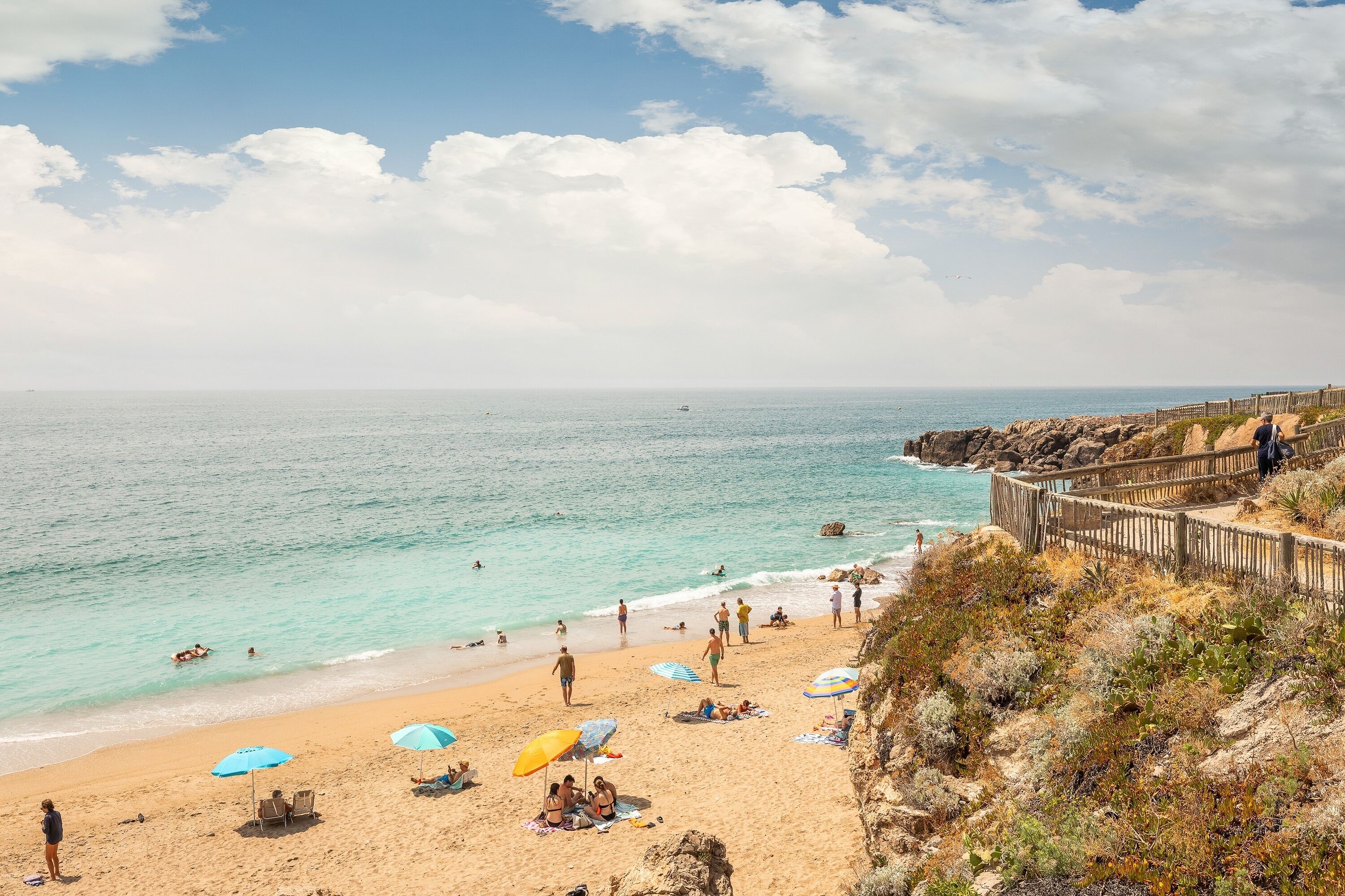Une plage où l’on peut voir des gens se prélasser au soleil, nager et se promener le long du rivage.