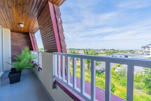 A balcony with a view of a residential area, a potted plant, and a red railing. - Duplex Panorama - À moins d'1 km de la plage (Courseulles-sur-Mer)
