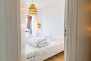 A bedroom with a bed, a hanging light fixture, and a wall-mounted light. - Duplex Panorama - À moins d'1 km de la plage (Courseulles-sur-Mer)