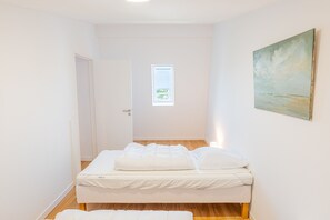 A bedroom with a bed, a door, a window, and a painting on the wall. - Duplex Panorama - À moins d'1 km de la plage (Courseulles-sur-Mer)