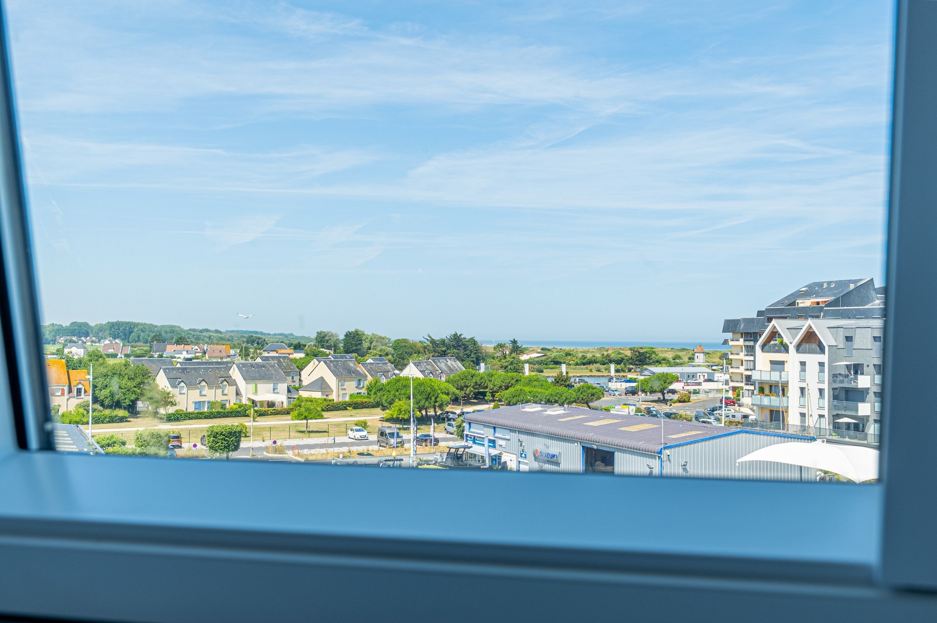 A residential area with houses, a Suzuki dealership, and a view of the sea.