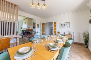 Een eethoek met een lange houten tafel, gedekt voor een maaltijd, omringd door stoelen.