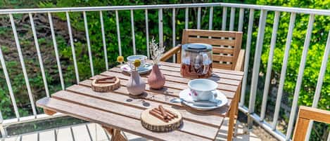 Mesa de madera al aire libre, con una baranda blanca al fondo.
