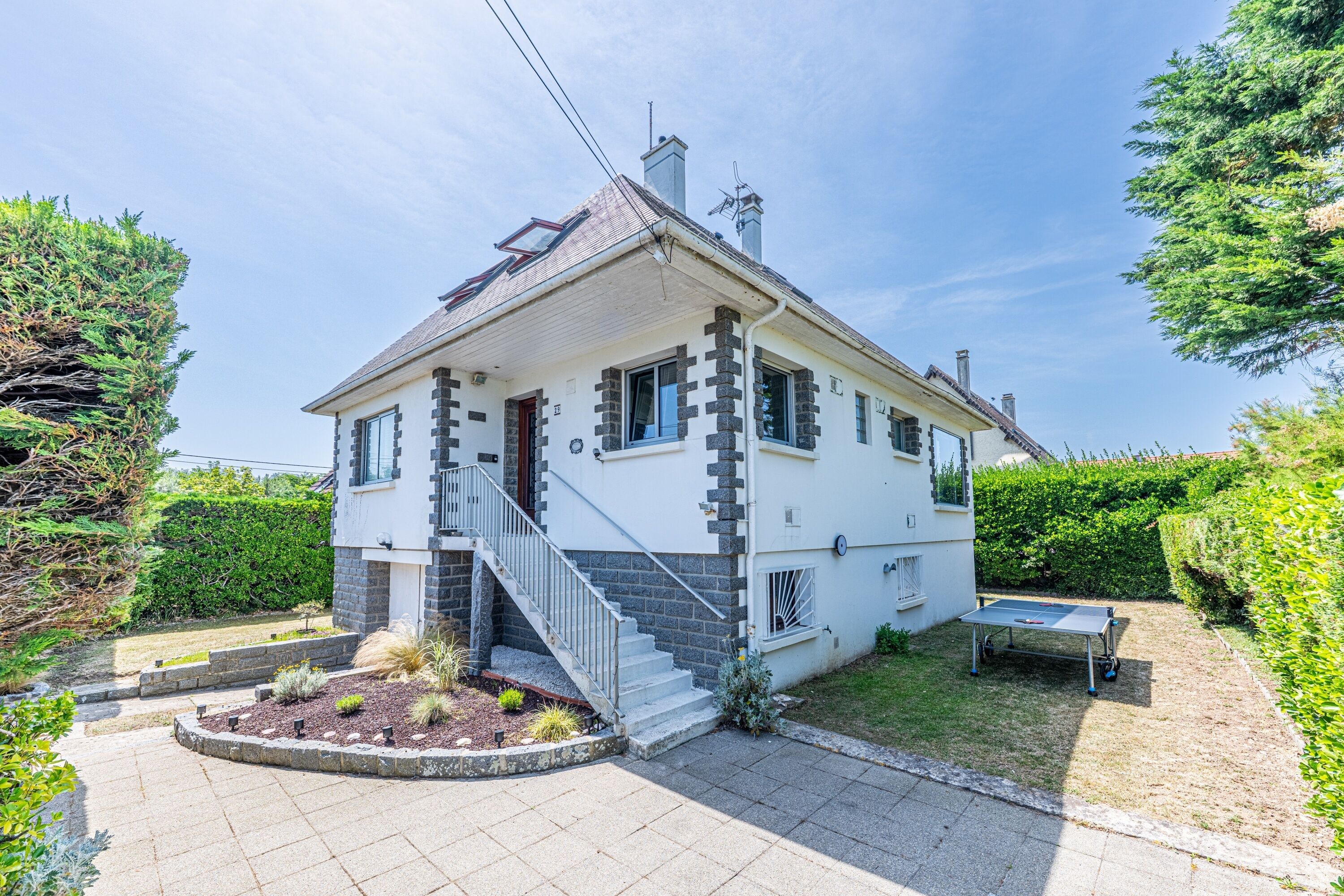 Une maison à deux étages avec un porche à l’avant, un escalier et un petit jardin.