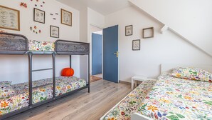 Una habitació amb lliteres, escriptori i una porta que dóna a una altra habitació.