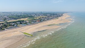 Vista aèria d'una zona costanera amb una platja de sorra, un passeig marítim i edificis residencials.