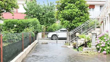 A gated driveway leading to a building with a white car parked inside.