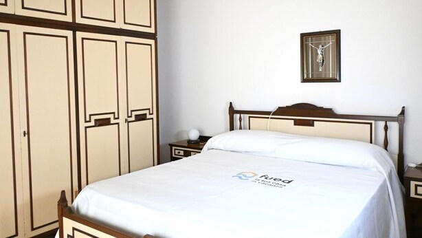 Un dormitorio con cama, mesita de noche, un cuadro en la pared y armario.