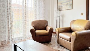 Una habitación con dos sillones de cuero, una lámpara de pie y un cuadro en la pared.
